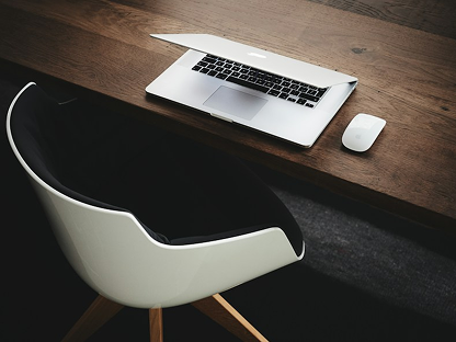 Laptop on a wooden desk with a white chair
