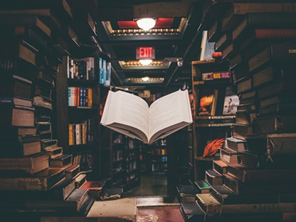 Open book floating between library shelves